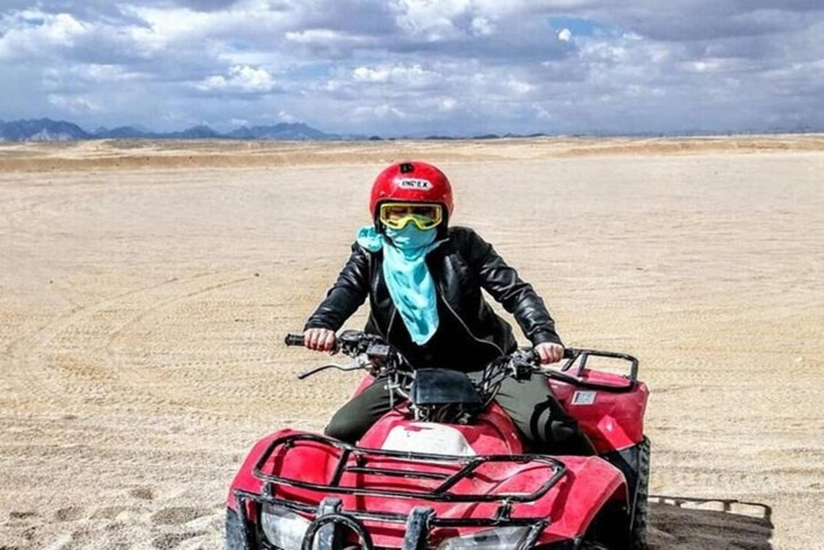 seseorang yang menunggang basikal quad di padang pasir