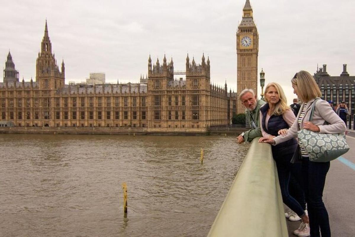 two women and a man standing on the edge of a building with big ben