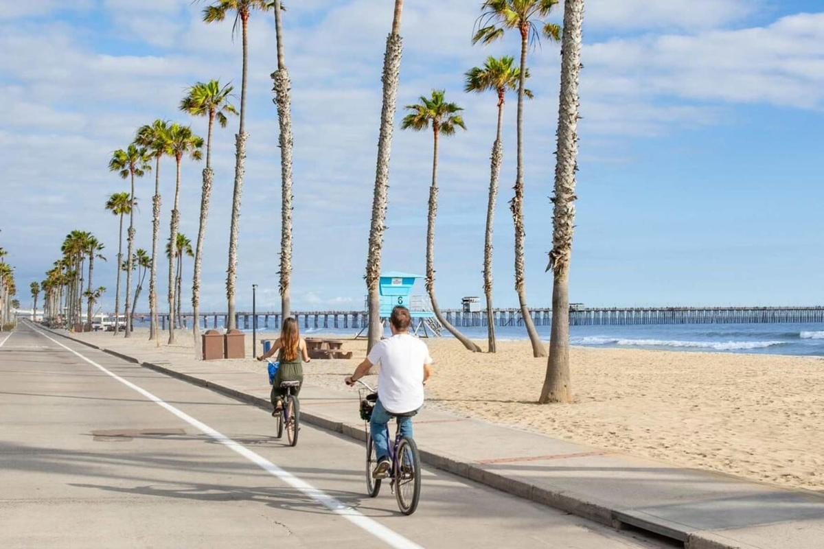 a man and a woman riding bikes down the beach