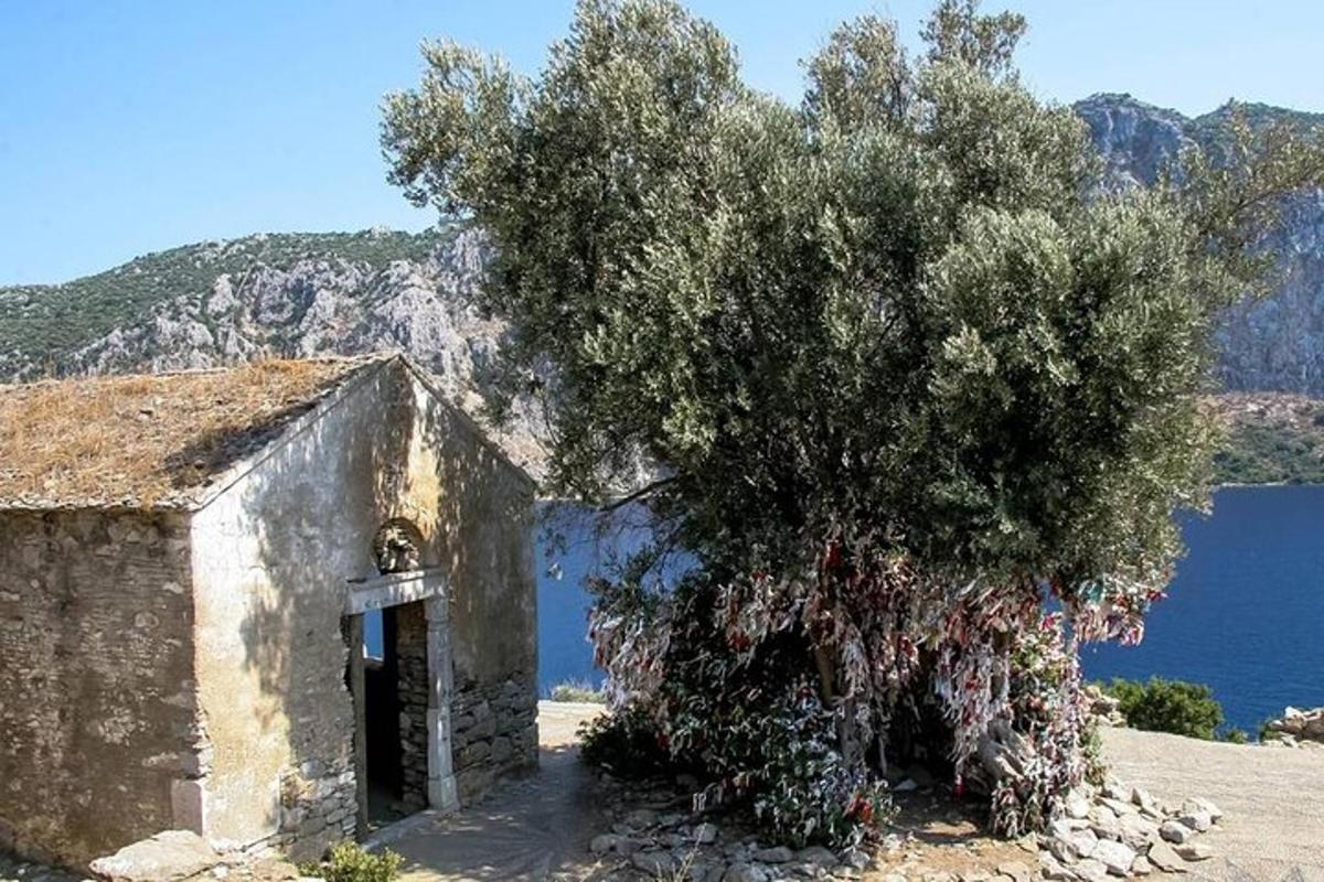 an old building with a tree next to the water