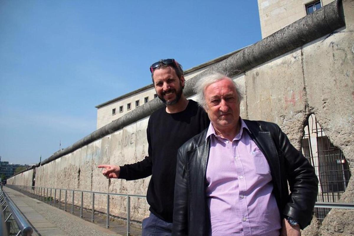 dois homens estão parados perto de uma parede