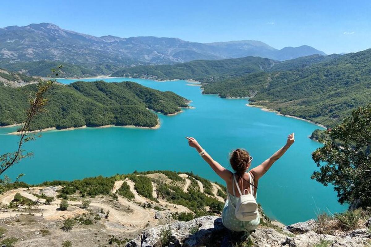 žena sedící na vrcholu hory s výhledem na jezero