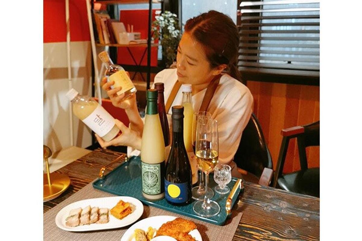 uma mulher sentada à mesa com duas garrafas de vinho