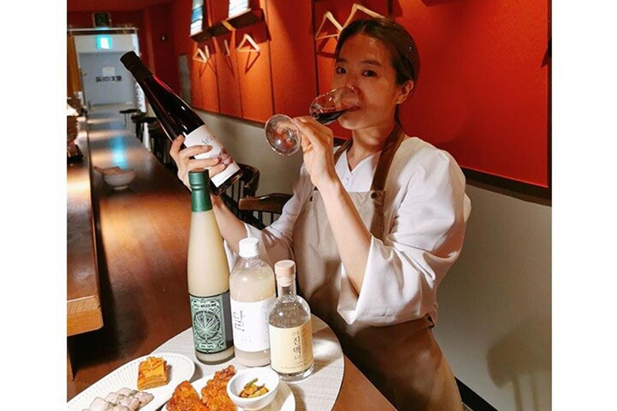 una donna seduta a un tavolo che beve una bottiglia di vino