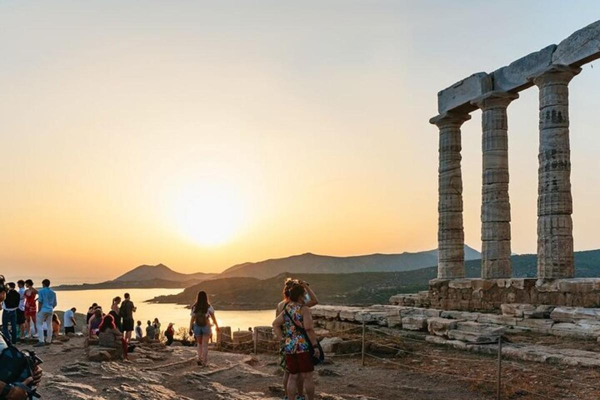 people standing at the temple of poseidon at sunset