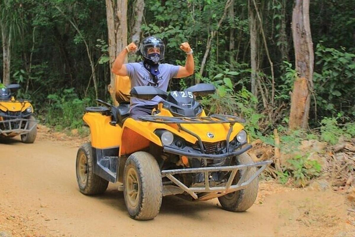 un homme conduisant un véhicule à quatre roues sur un chemin de terre