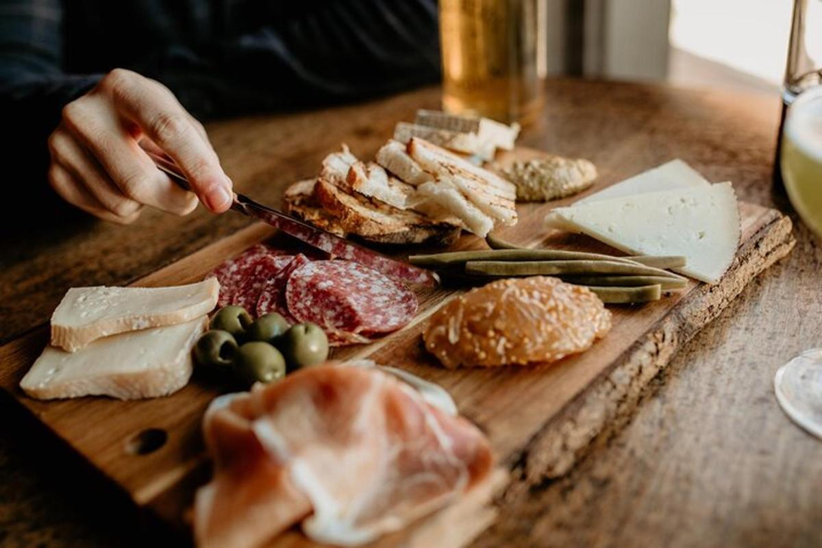 a person is cutting cheese on a wooden cutting board