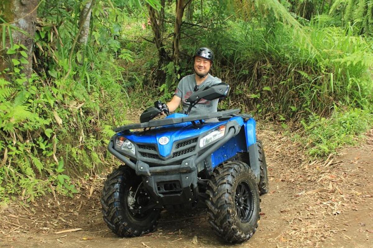 un home conduint un quad per un camí de terra