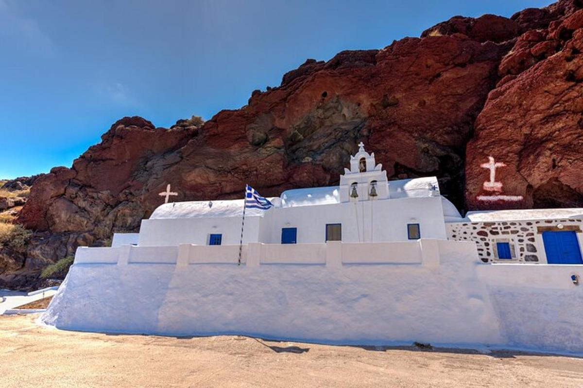 una chiesa bianca di fronte a una montagna rocciosa
