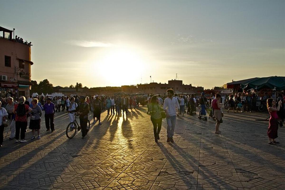 una multitud de personas caminando por una calle al atardecer