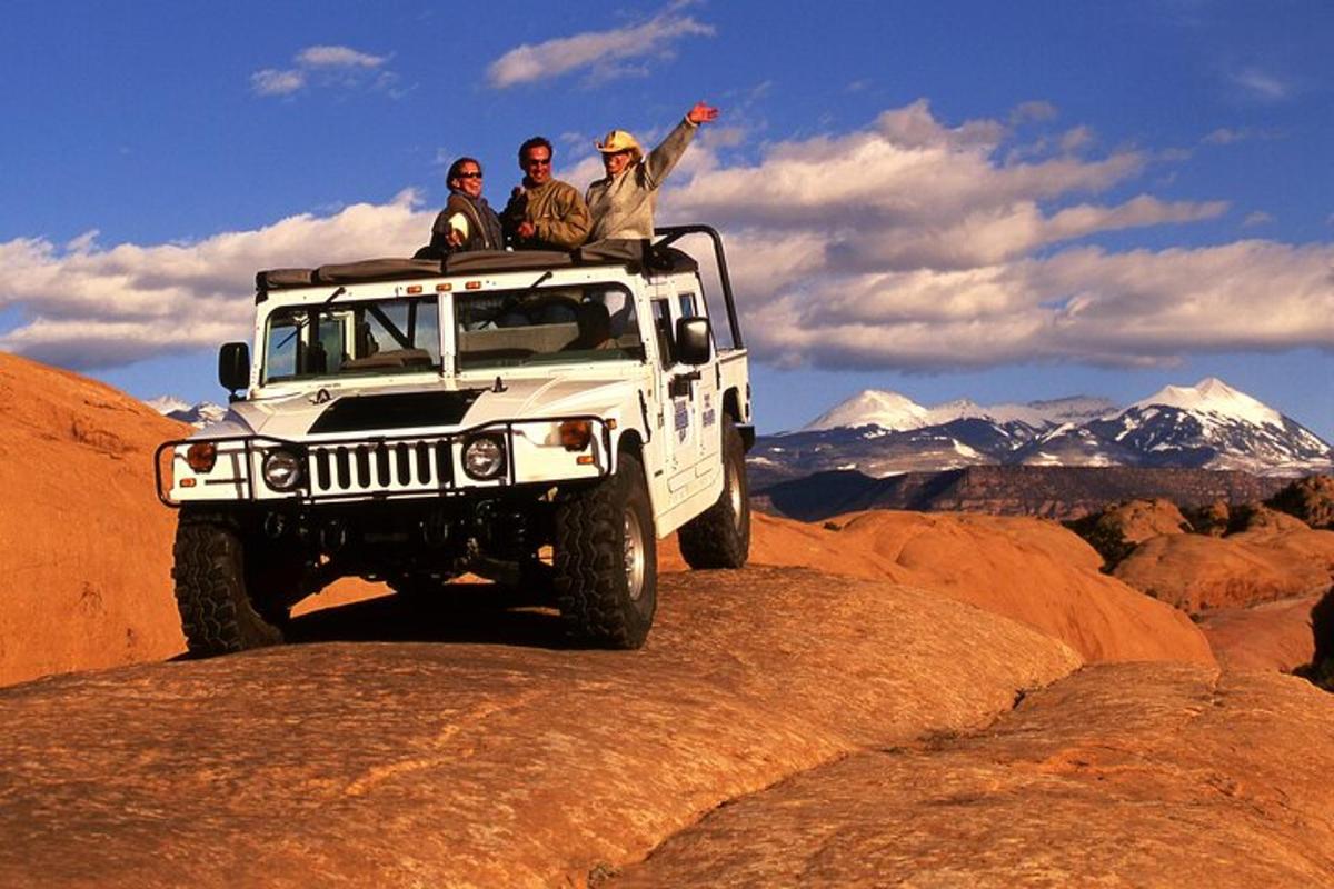 three people sitting on top of a jeep on a mountain