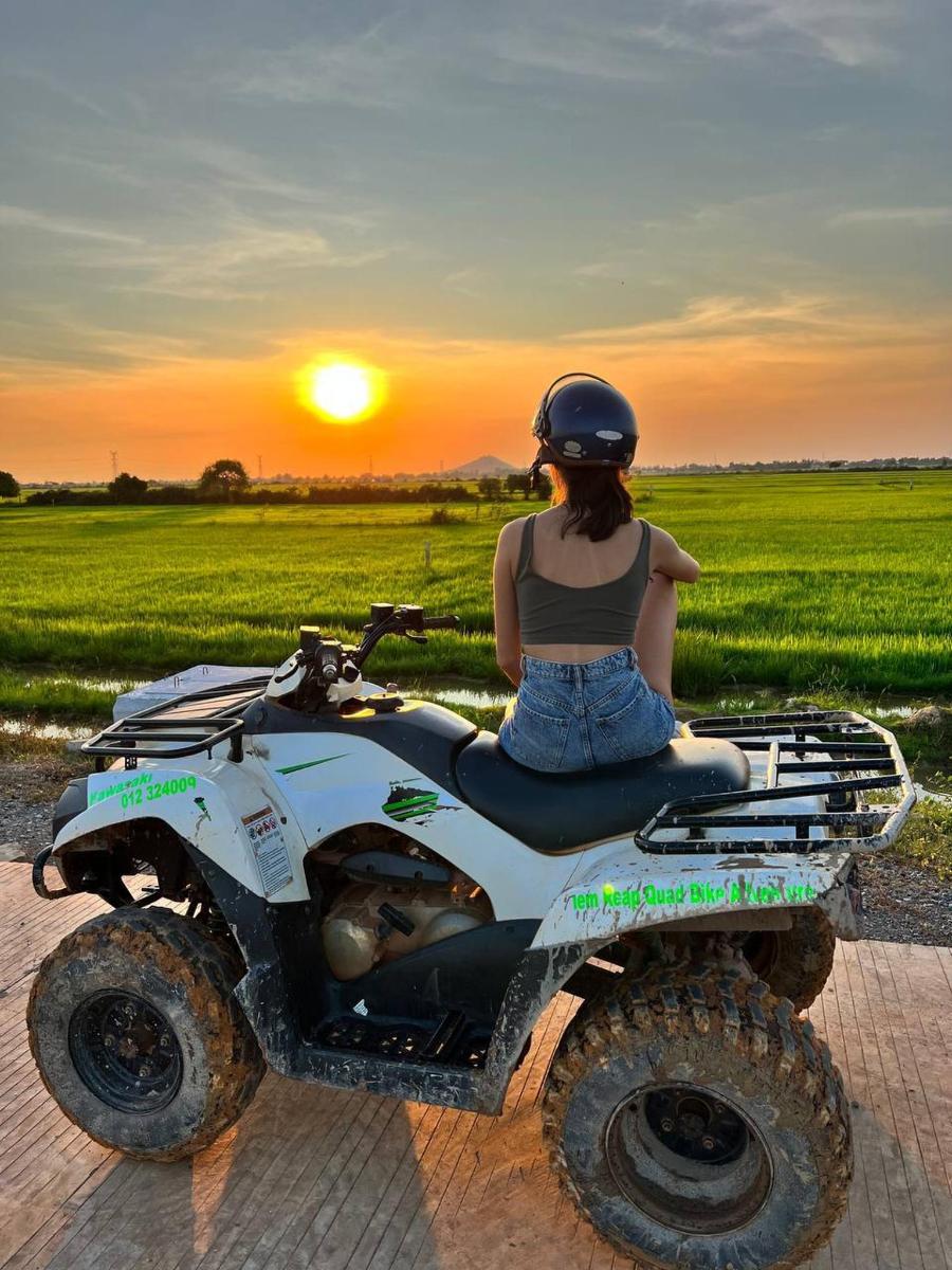 a woman sitting on a quad bike at sunset