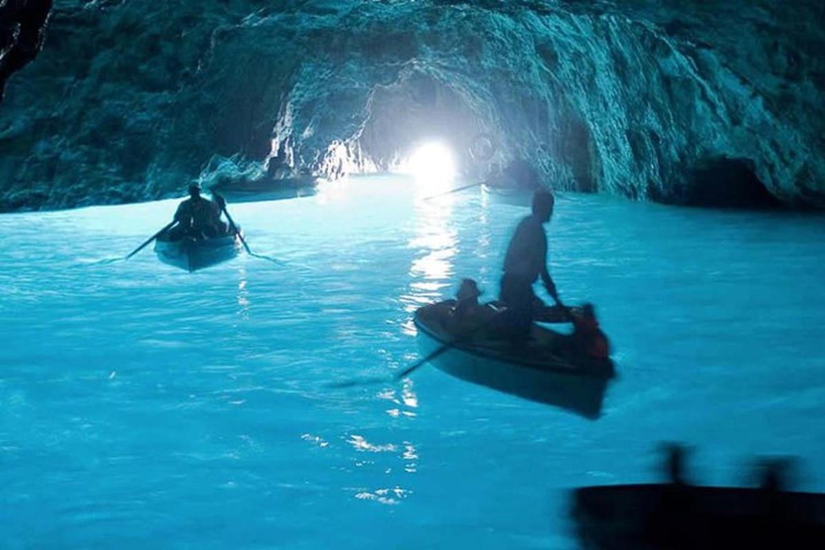 Dos personas en botes en una cueva azul