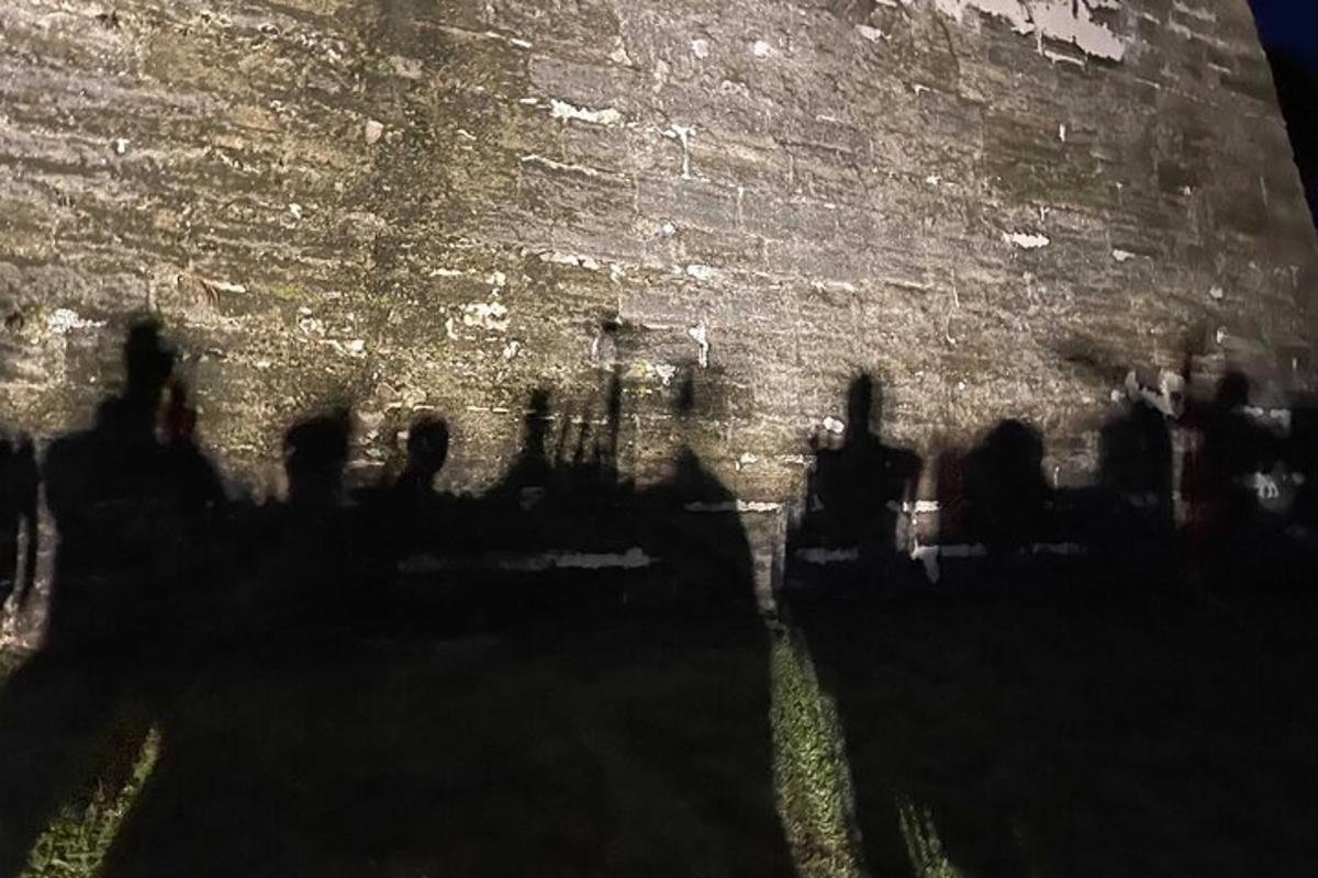 un grup de oameni care stau lângă un zid de cărămidă
