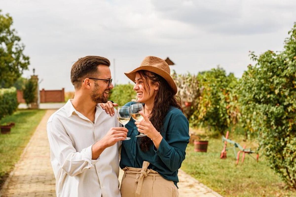 a man and woman drinking wine in an orchard