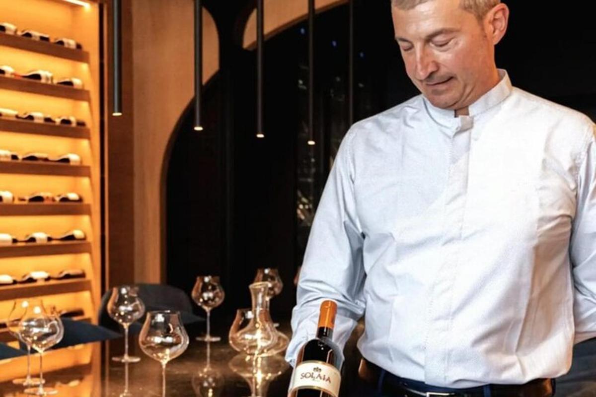 ένας άντρας που στέκεται σε ένα τραπέζι με ένα μπουκάλι κρασί