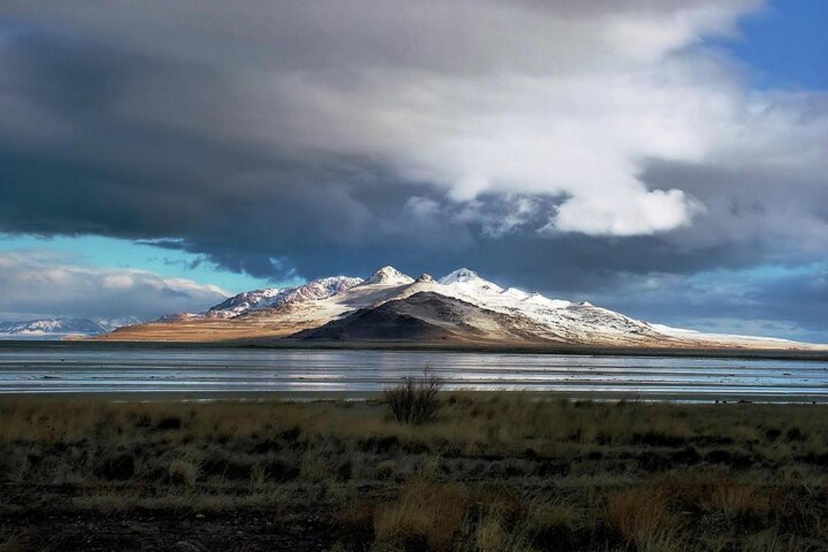 a snow covered mountain in front of a body of water