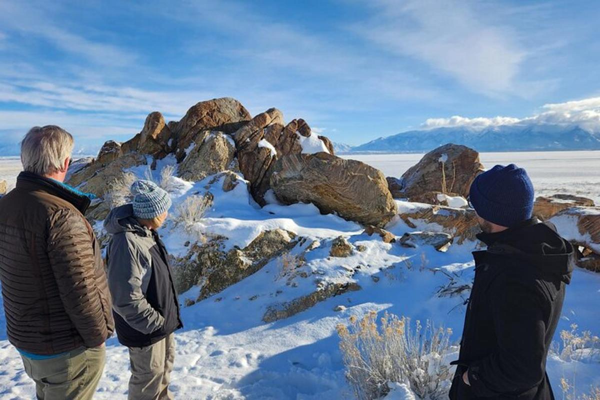 three people standing on top of a snow covered mountain