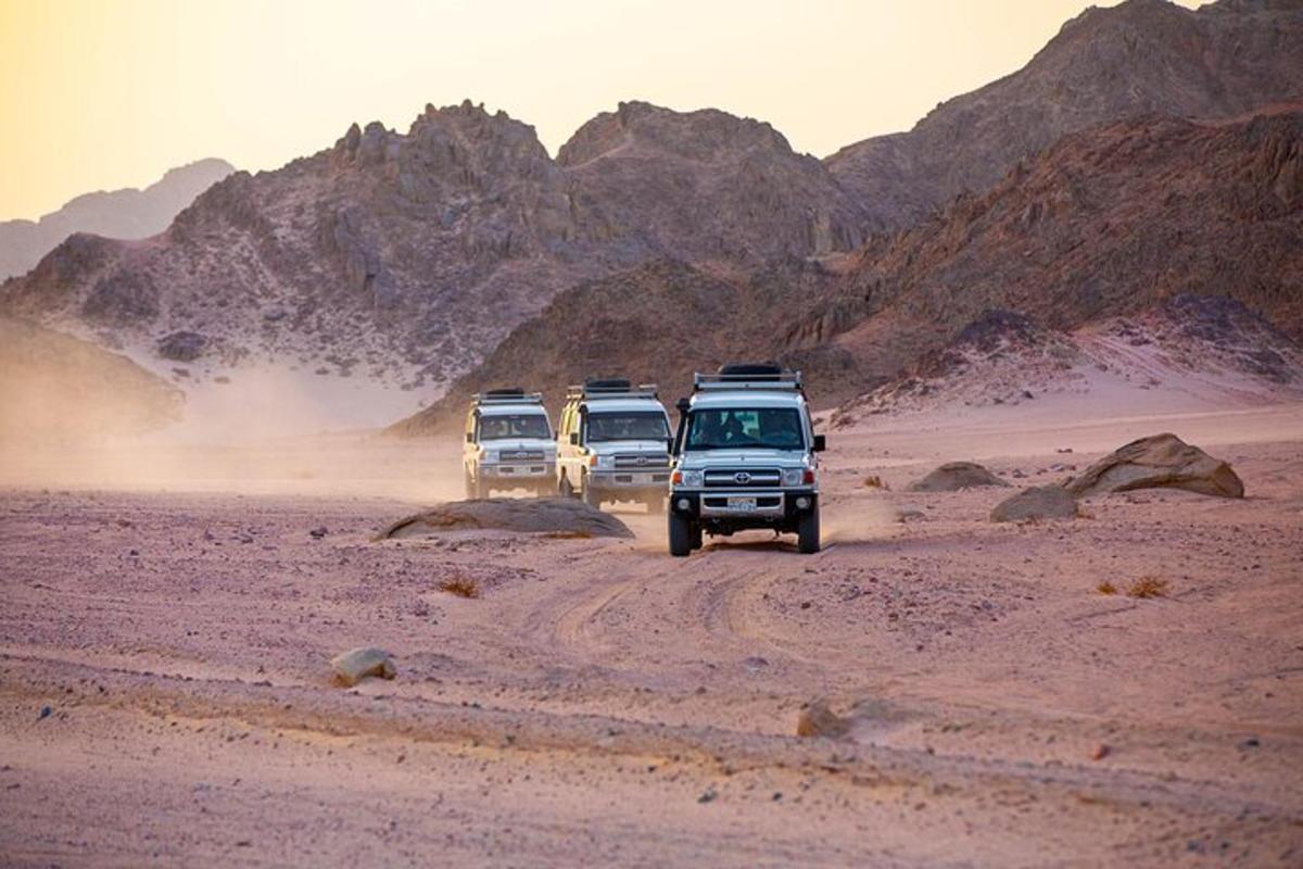 um grupo de três veículos dirigindo no deserto