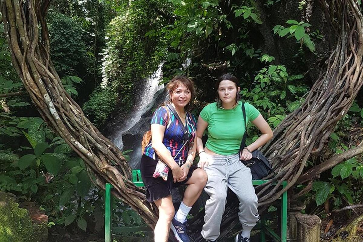 duas pessoas sentadas em uma ponte em frente a uma cachoeira