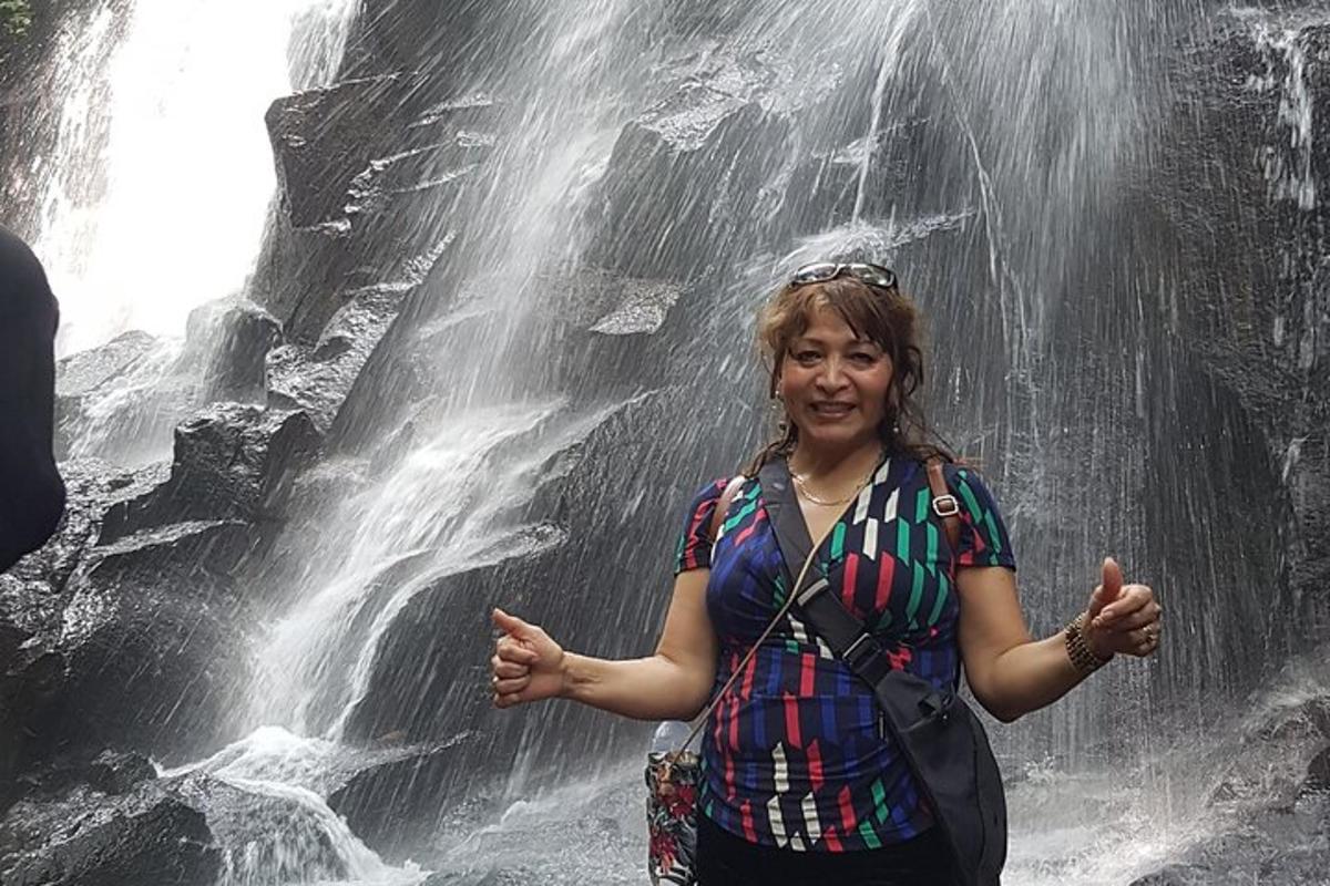 uma mulher parada em frente a uma cachoeira