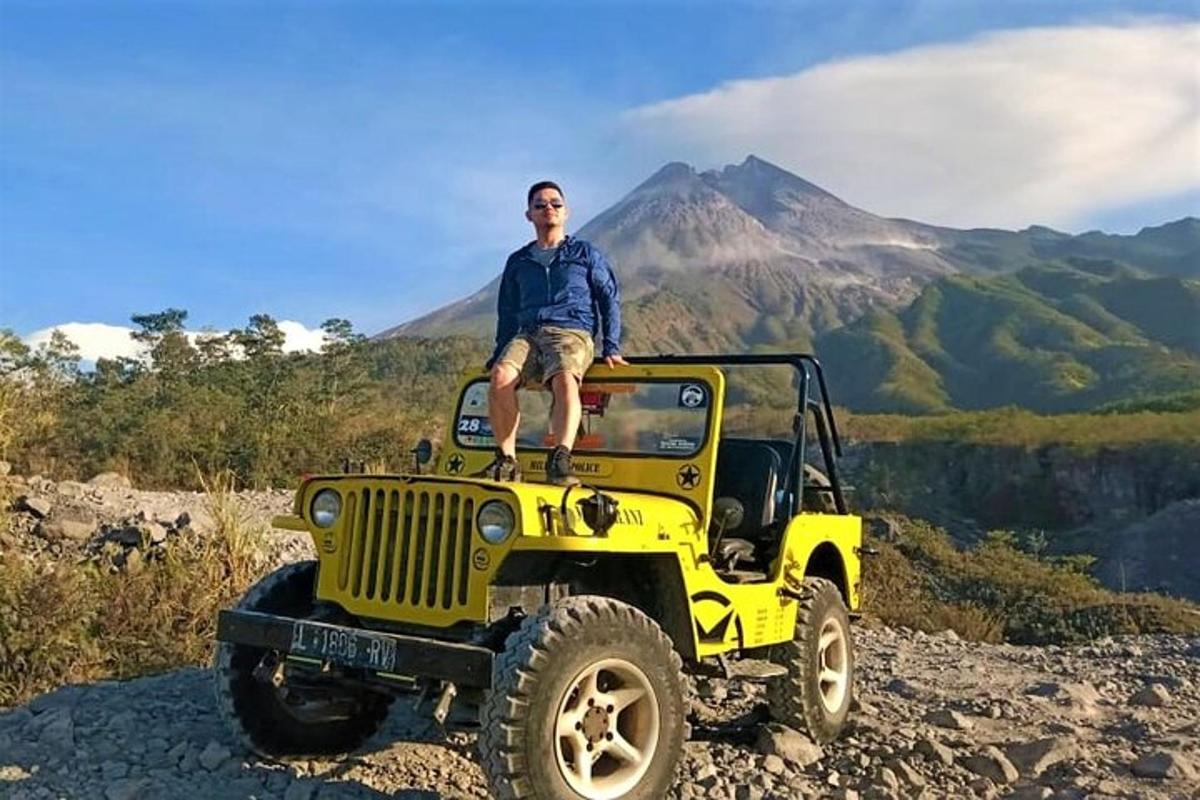 seorang lelaki duduk di atas sebuah jip di atas gunung