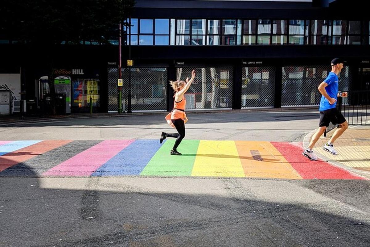 uma mulher correndo em uma faixa de pedestres com as cores do arco-íris