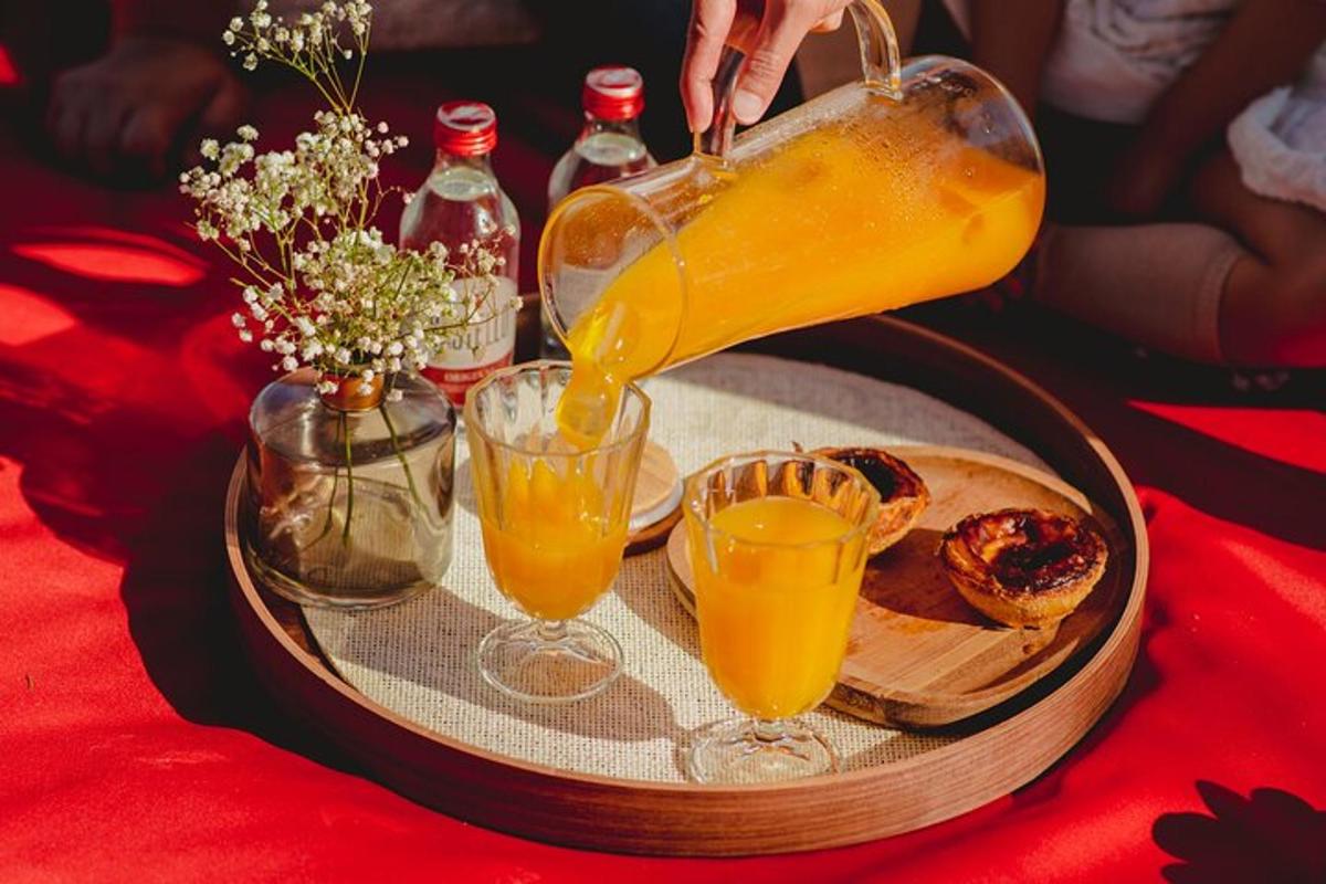 en person som heller appelsinjuice i to glass på et brett
