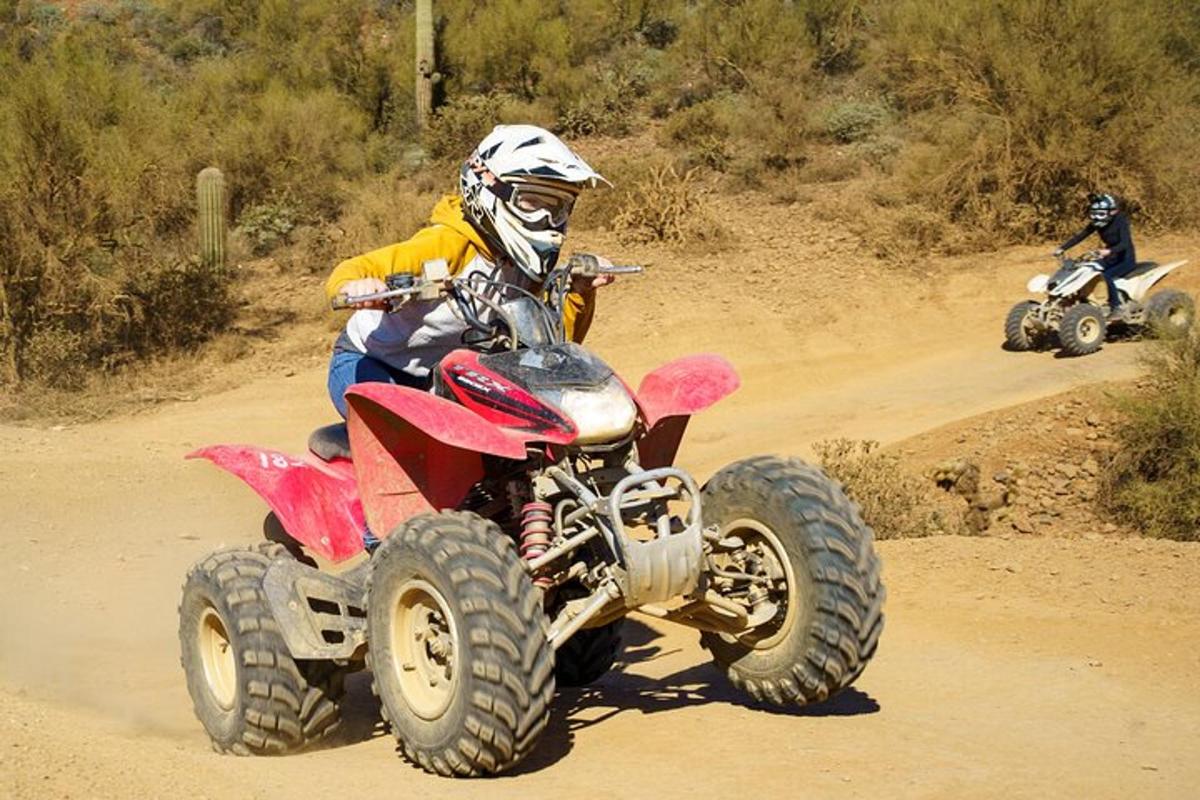 isang taong nakasakay sa isang four wheeler sa isang maruming kalsada