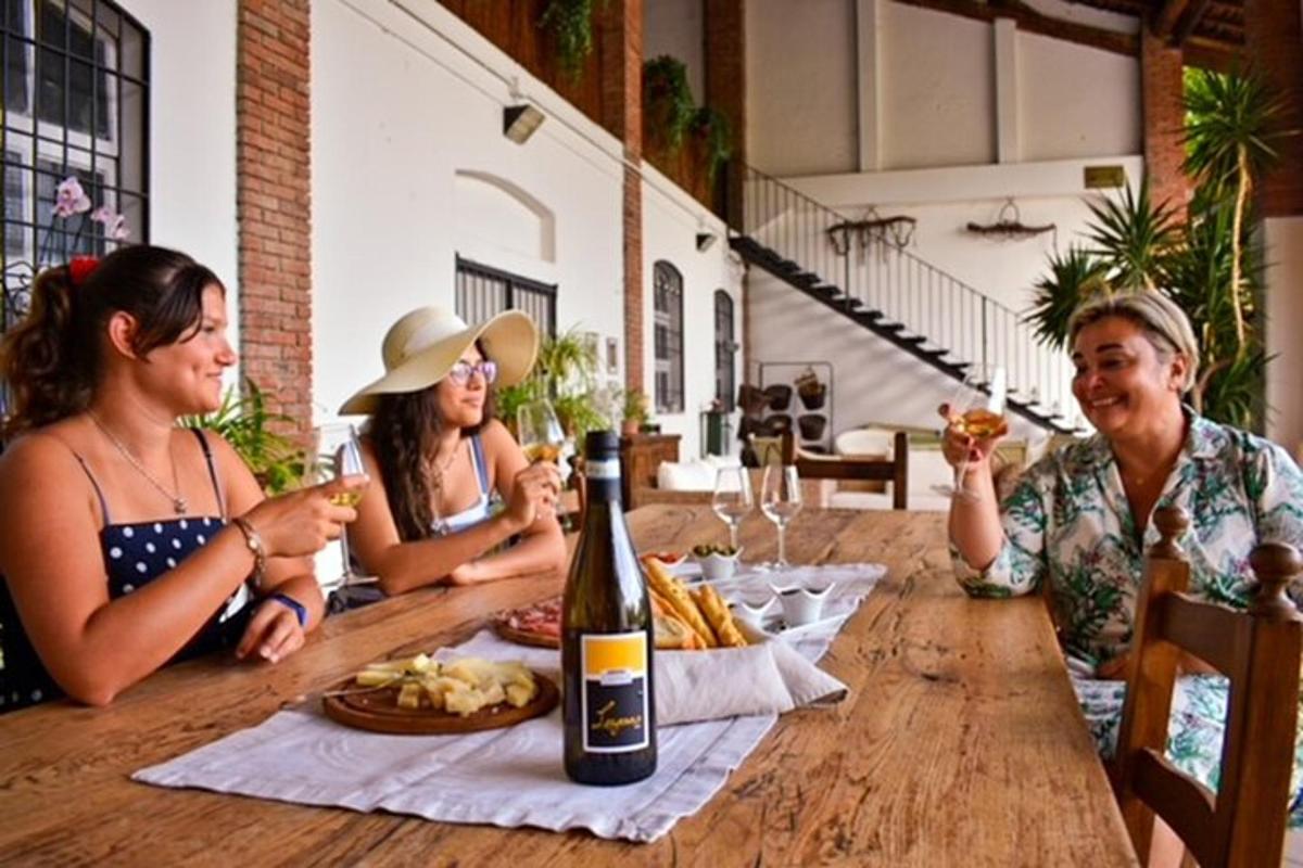 trije ljudje sedijo za mizo s steklenico vina