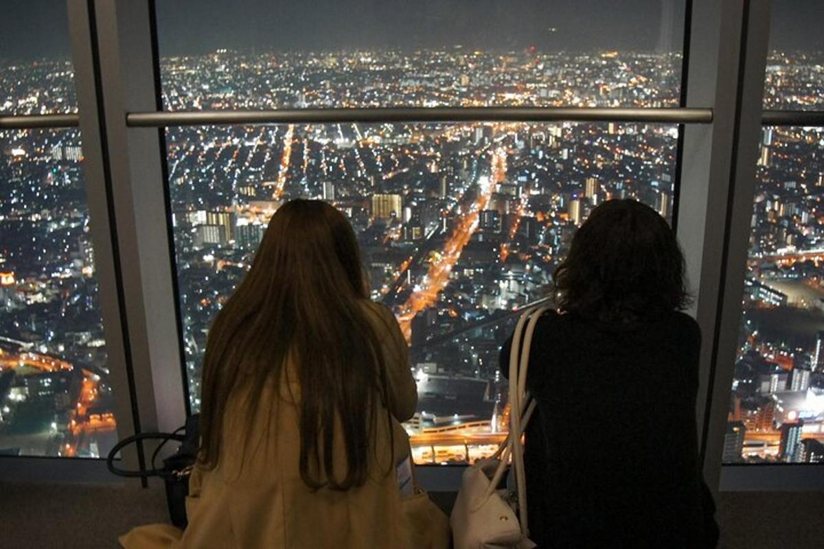 two women sitting on chairs looking out of a window at night