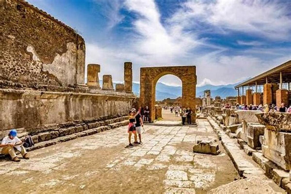 μια ομάδα ανθρώπων που στέκονται σε έναν δρόμο με μια αψίδα