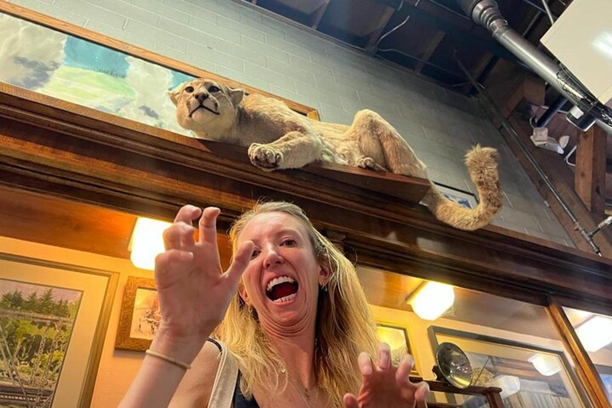 a woman holding her hands up in front of a lion sculpture