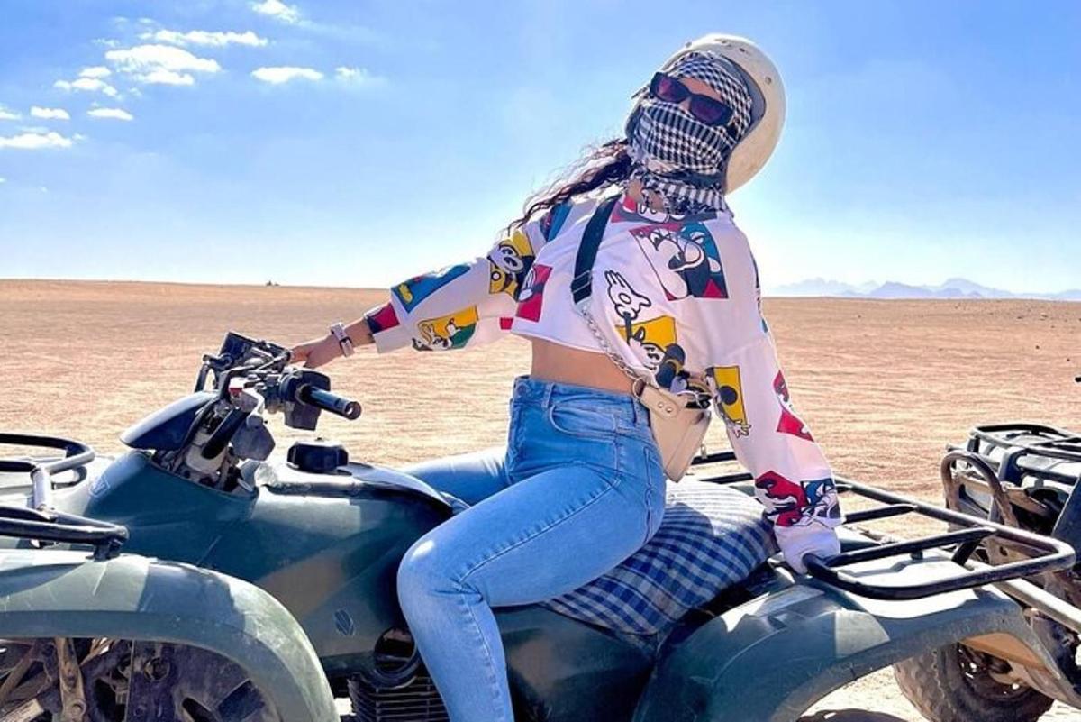uma mulher sentada em uma motocicleta no deserto
