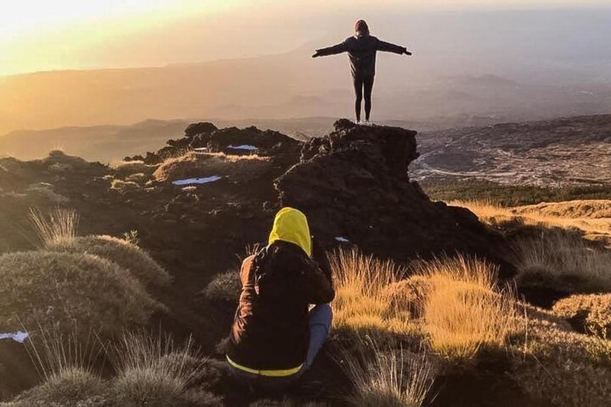 osoba stojící na vrcholu hory s rozpaženýma rukama