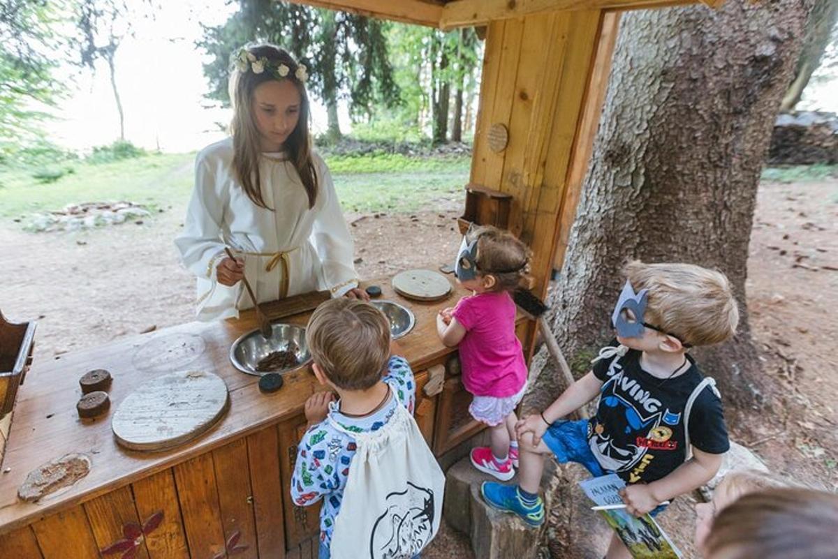 una donna e tre bambini in piedi attorno a un tavolo di legno