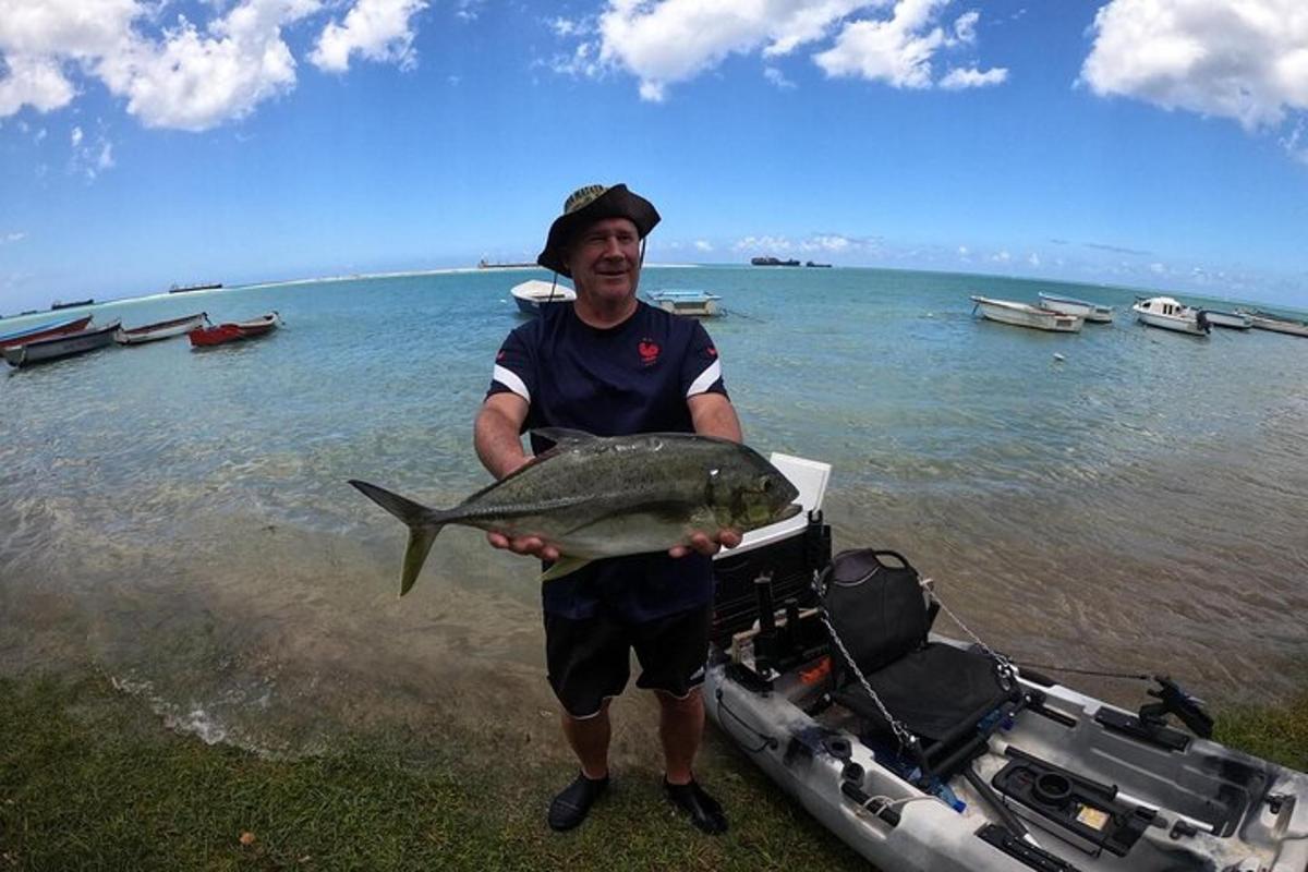 moški, ki drži ribo pred čolnom