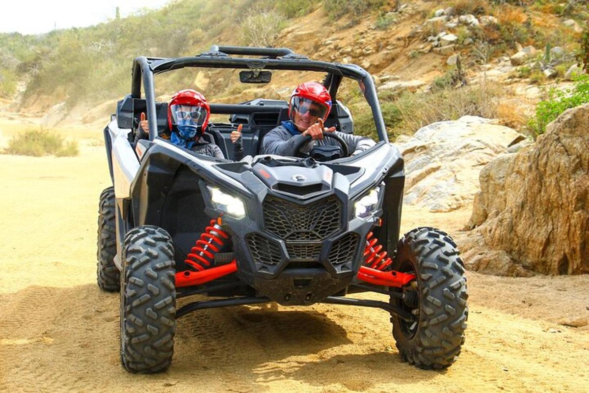 zwei Personen fahren auf einem Quad durch den Dreck