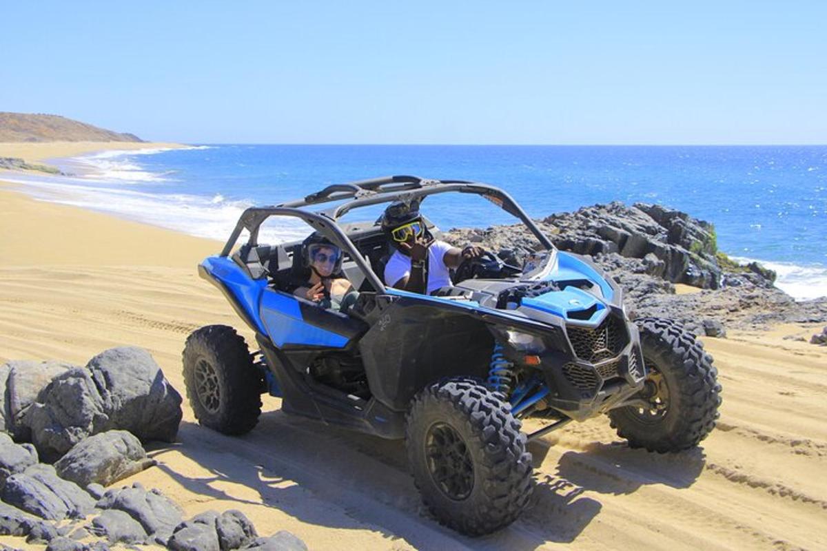 eine Gruppe von Menschen, die in einem Quad am Strand fahren