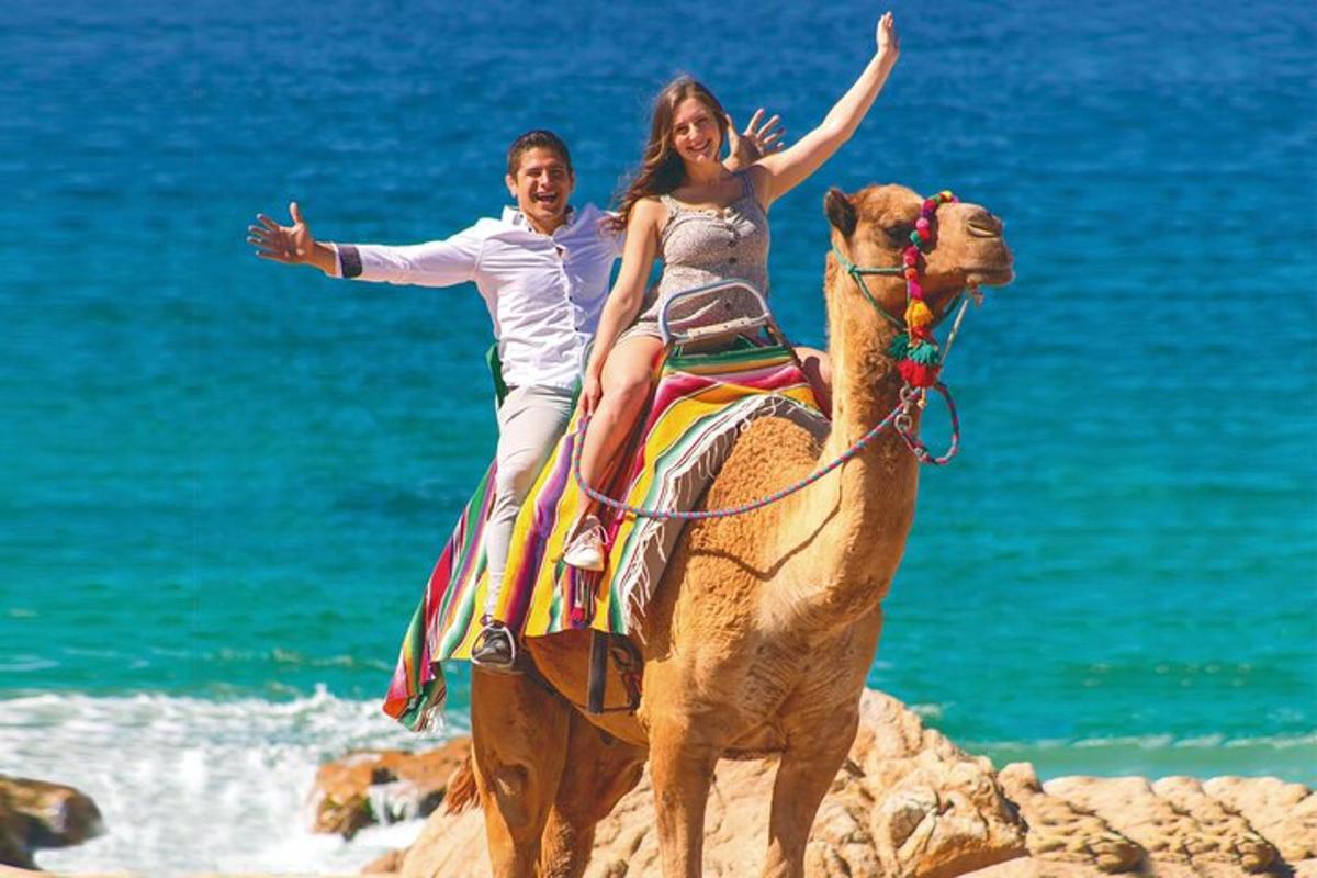Un hombre y una mujer montando un camello en la playa