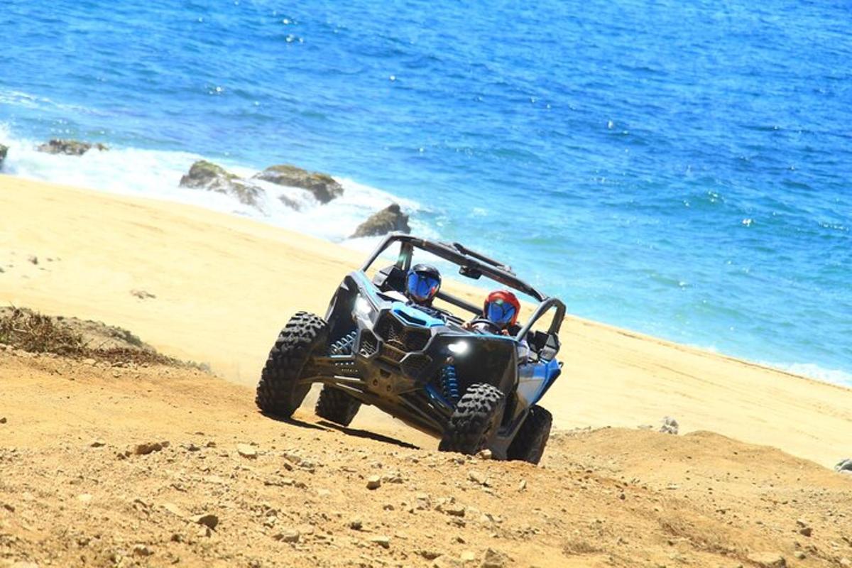 en blå ATV kører på sandet på stranden