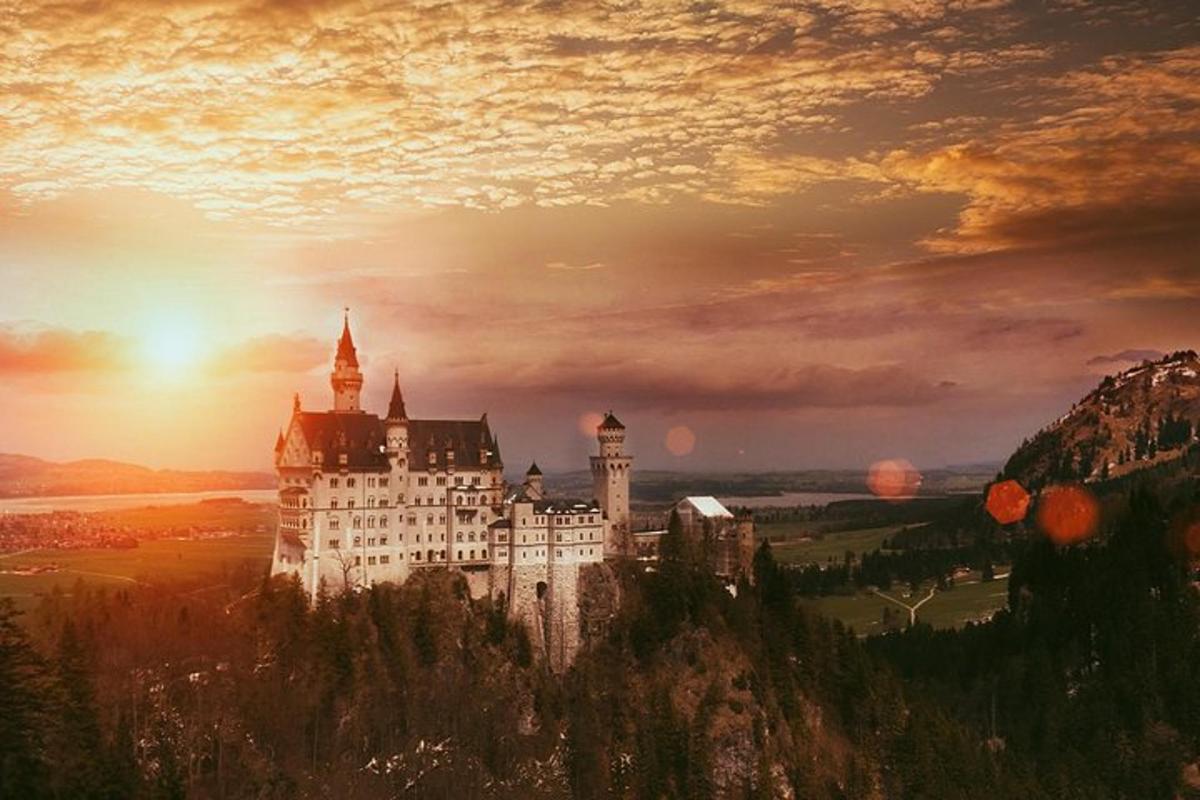 un castel pe vârful unui munte cu un apus de soare