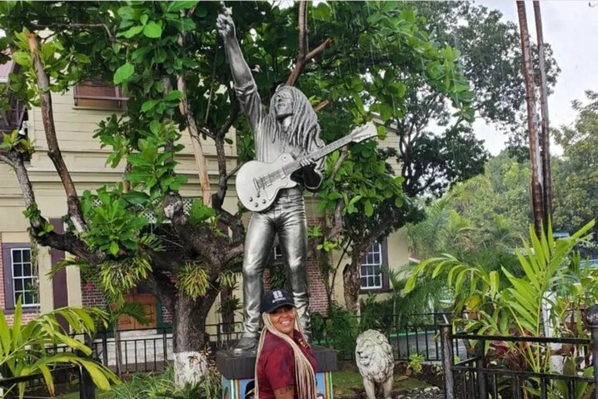 un home dret davant d'una estàtua d'un home que sosté una guitarra
