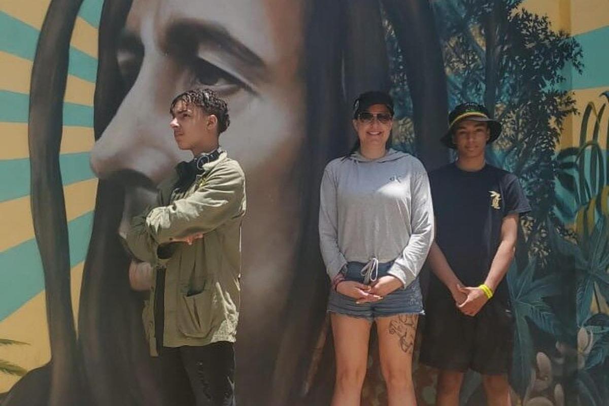 Tres hombres de pie frente a un cuadro de una mujer