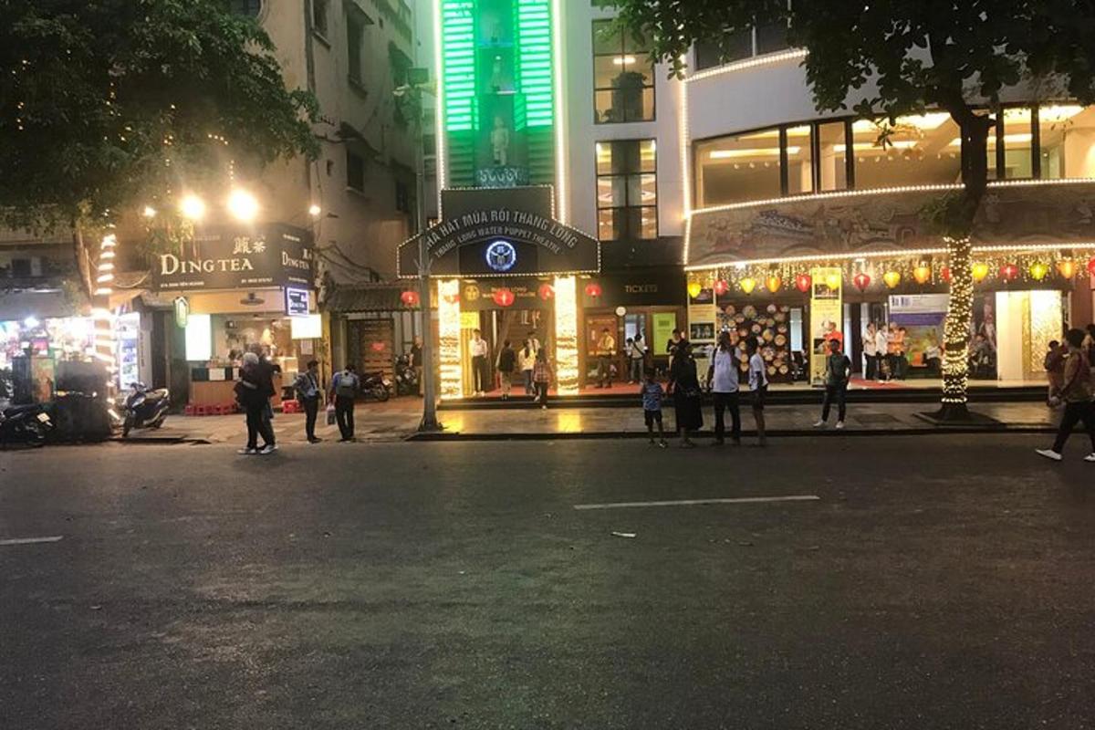 jalan bandar pada waktu malam dengan orang ramai berjalan di hadapan kedai