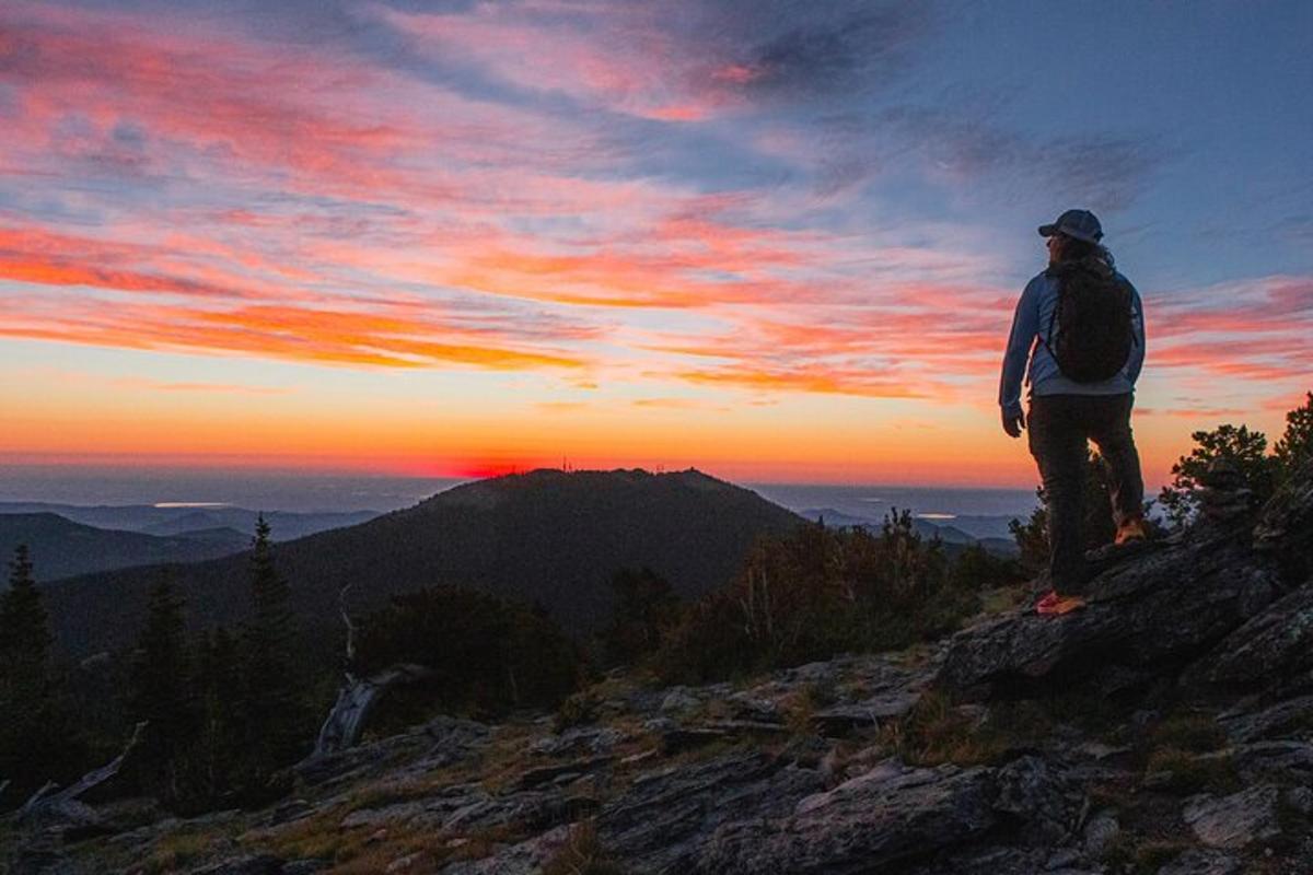 a man standing on top of a mountain watching the sunset
