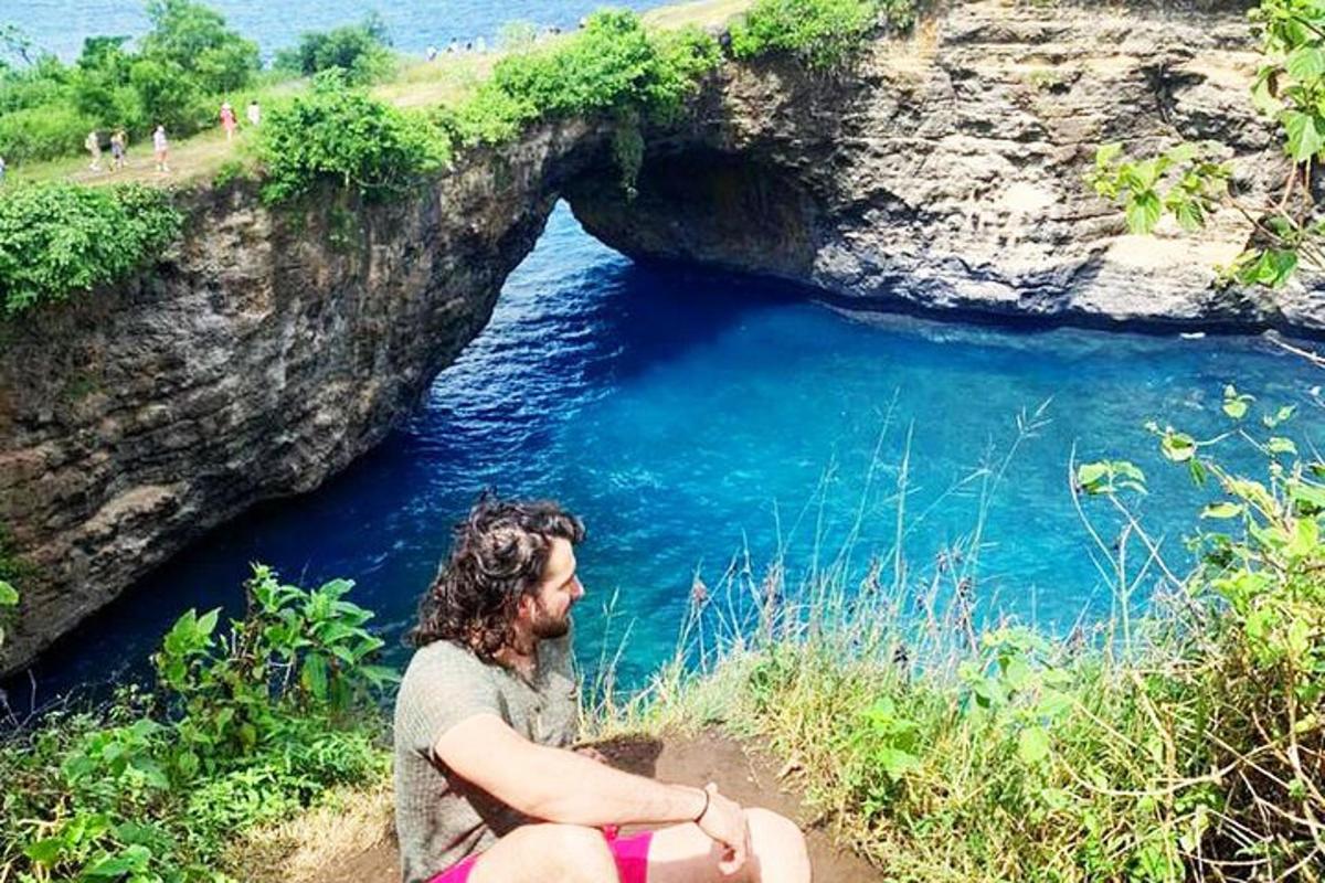 una donna seduta su una scogliera accanto a uno specchio d'acqua