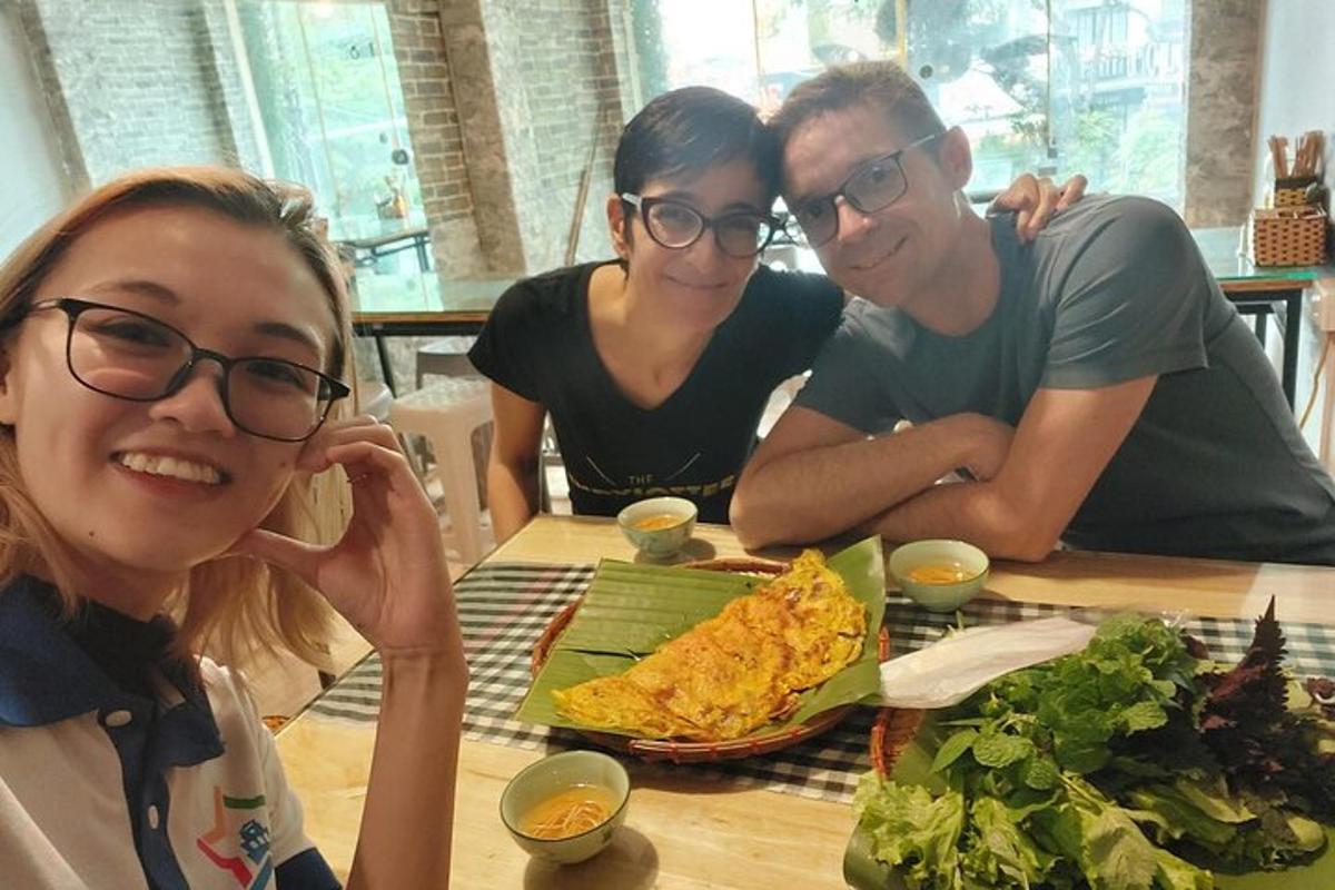 three people sitting at a table with a plate of food
