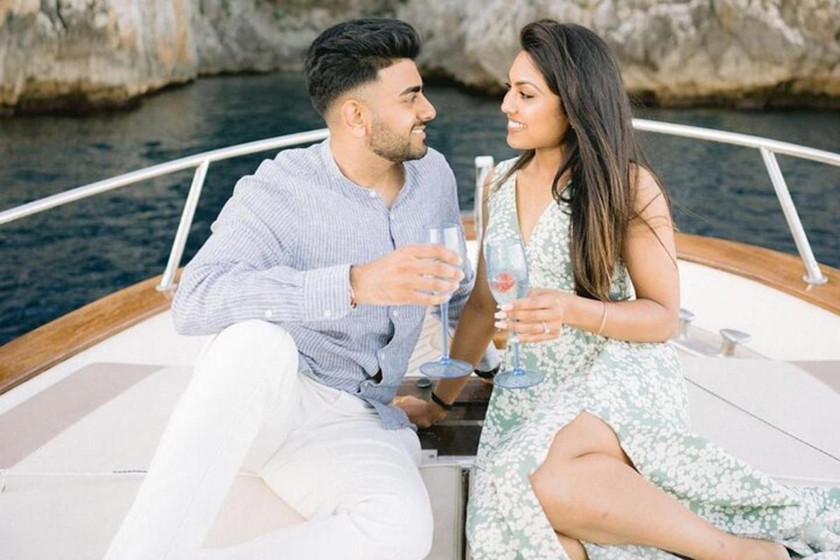 un uomo e una donna seduti su una barca con bicchieri di vino
