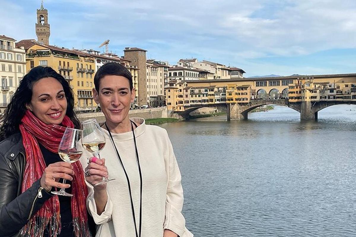 Un hombre y una mujer sosteniendo copas de vino frente a un río.